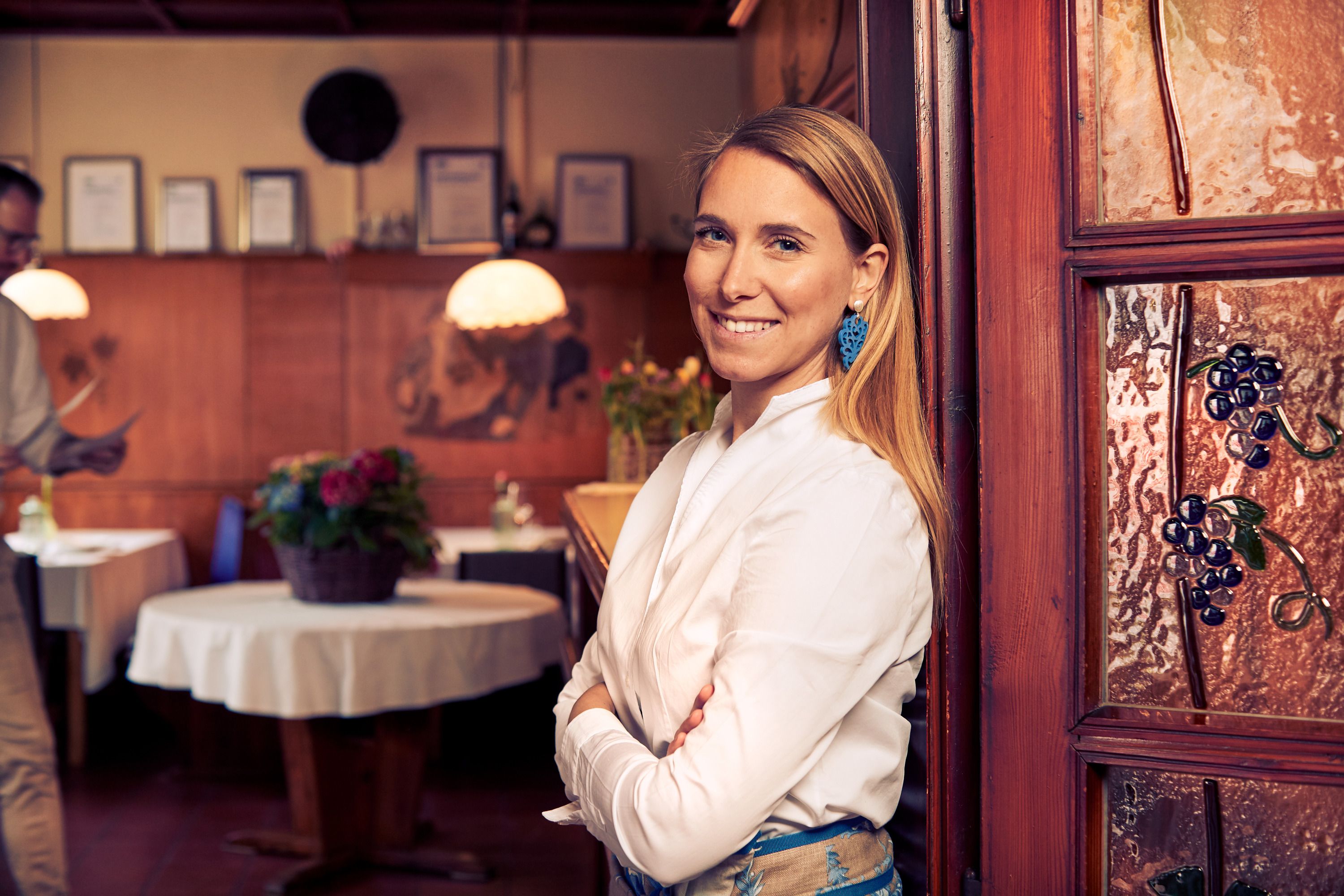 Woman in a white shirt smiles in a traditional restaurant with wooden furnishings.