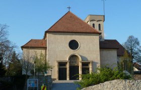 Front view of a church with a red roof and round window.