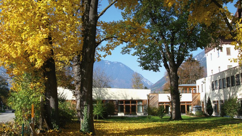 Autumn scene with hotel building and yellow leaves on the ground.
