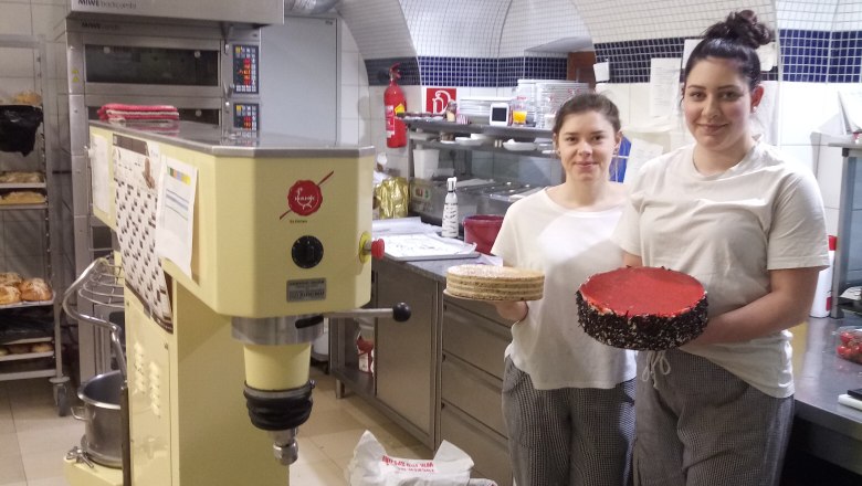 Two people in a bakery with a cake and a cake base.