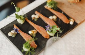 Gourmet dish with salmon, herbs and flowers served on a slate plate.
