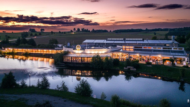 Cheese maker's world building at sunset, illuminated and situated on the water.
