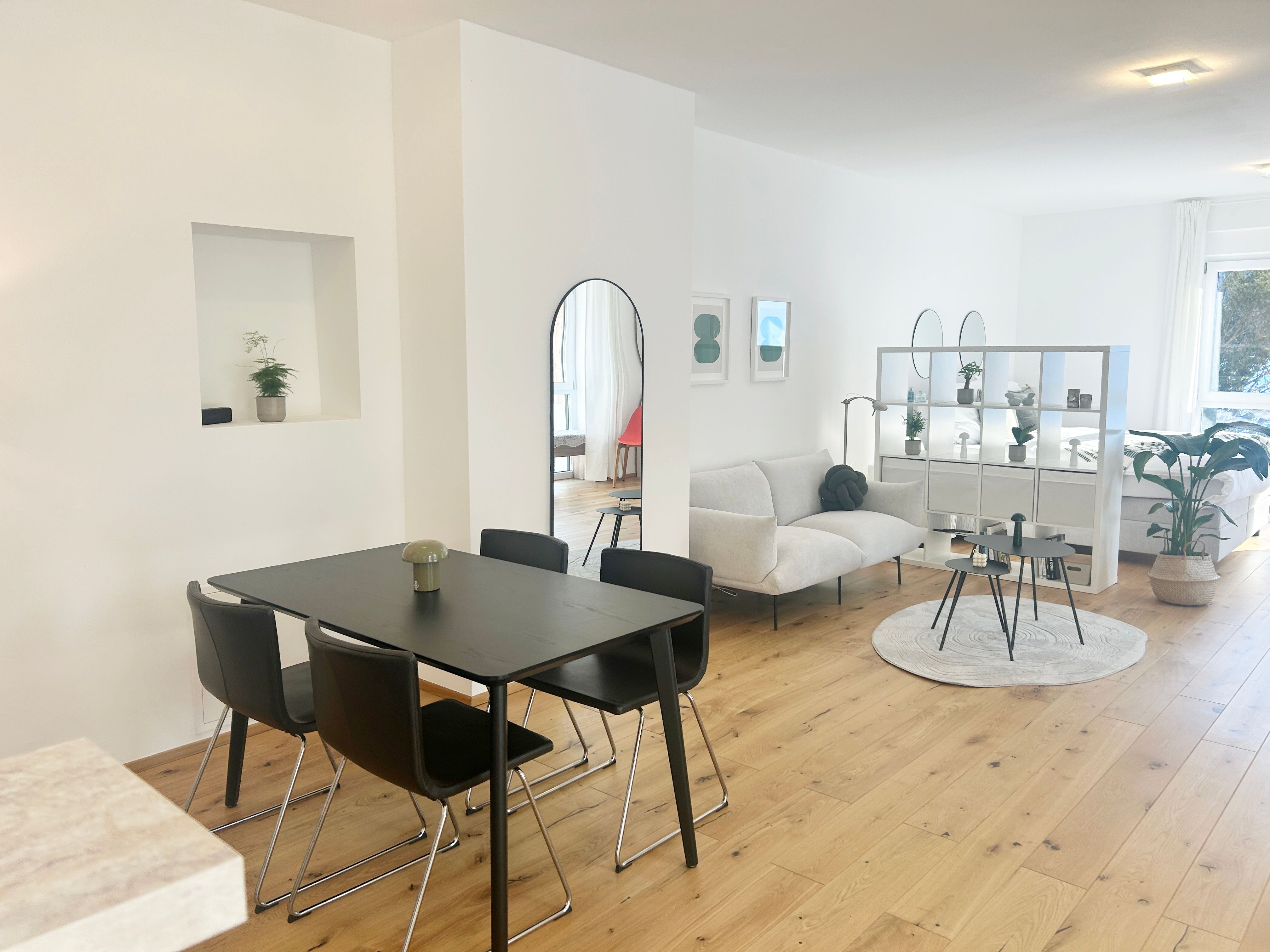 Modern living room with dining table, sofa and shelves in an open space.