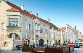 Historic buildings in Eggenburg with ornate facades and a street caf&eacute; in the foreground.