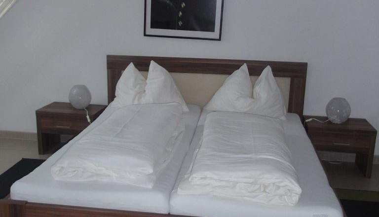 Gasthof Prinz, © GH Prinz Double bed in a hotel room with white bed linen and a plant picture on the wall.