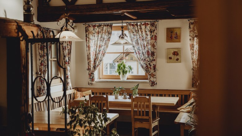 Cozy room with wooden furniture, plants and flowered curtains.