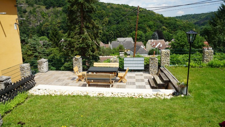 Pension Thayatalblick, © Jörg Riffer Terrace with wooden furniture and views of a village and wooded hills.