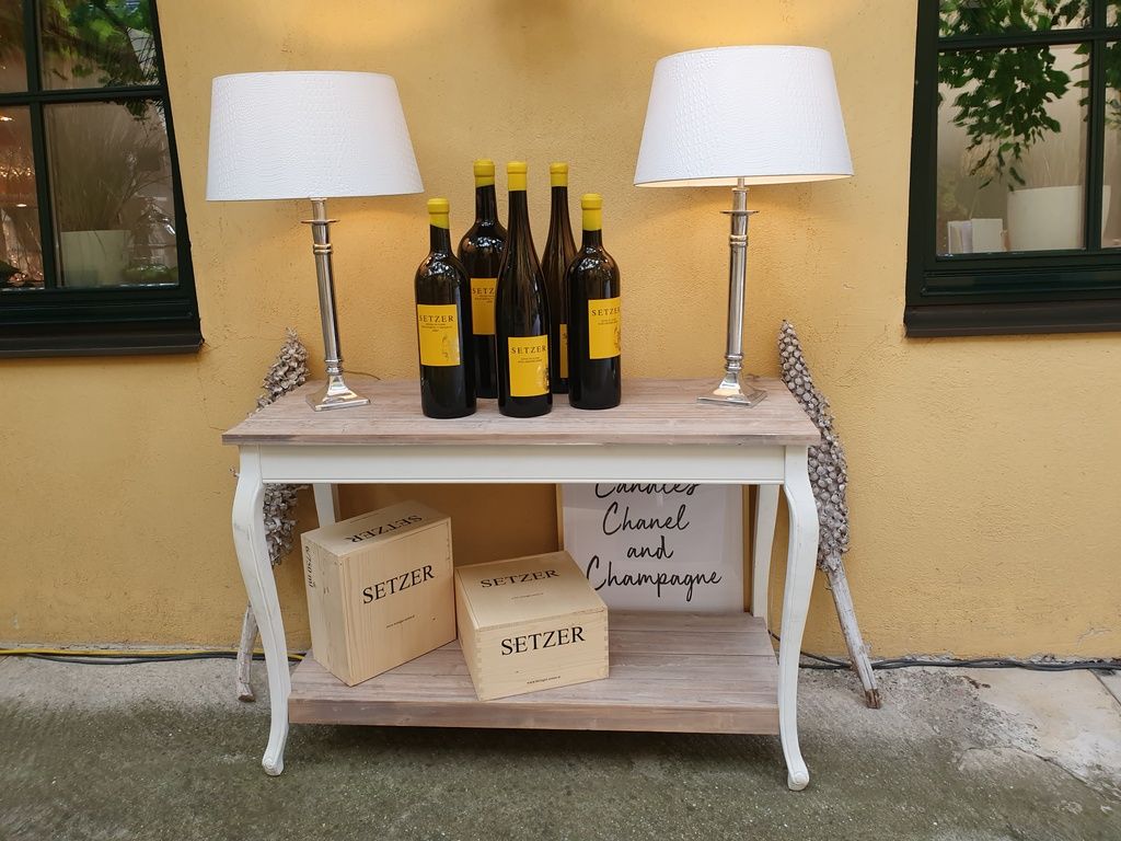 Console table with wine bottles, lamps and wooden boxes.