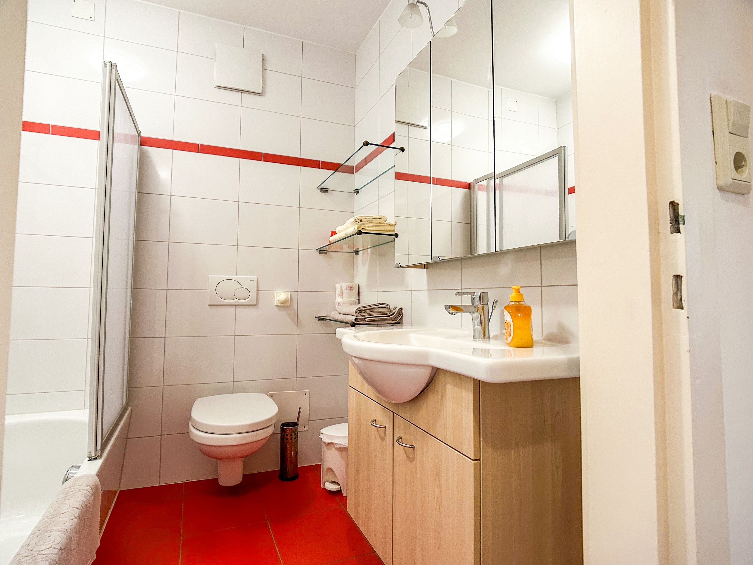 Modern bathroom with red tiles, white ceramics and mirrors.