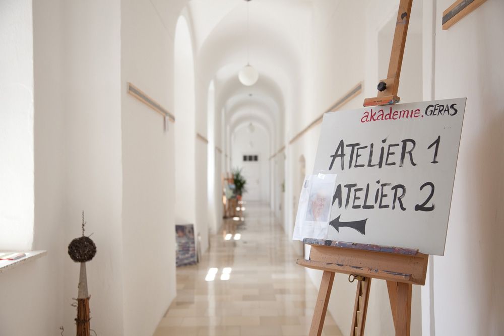 A bright hallway with a sign on an easel pointing to Atelier 1 and Atelier 2.