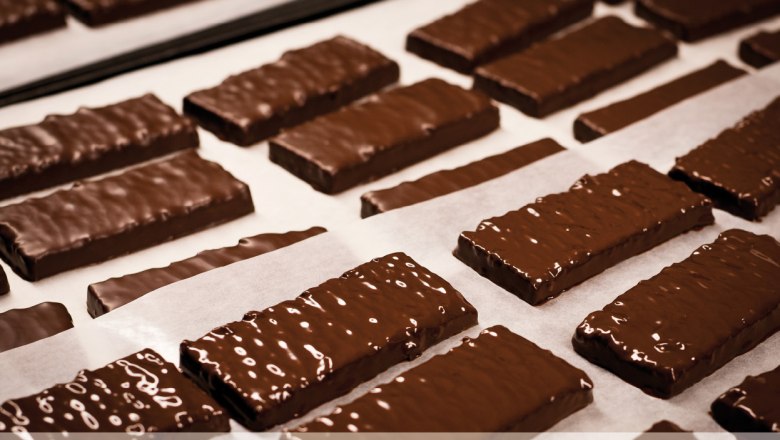Chocolate-covered cookies on baking paper in a patisserie.