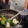 Cook stirs vegetables in a pan.
