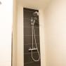 Modern shower with black and white tiled wall.
