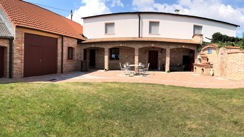 Brick building with garden and terrace in sunny weather.