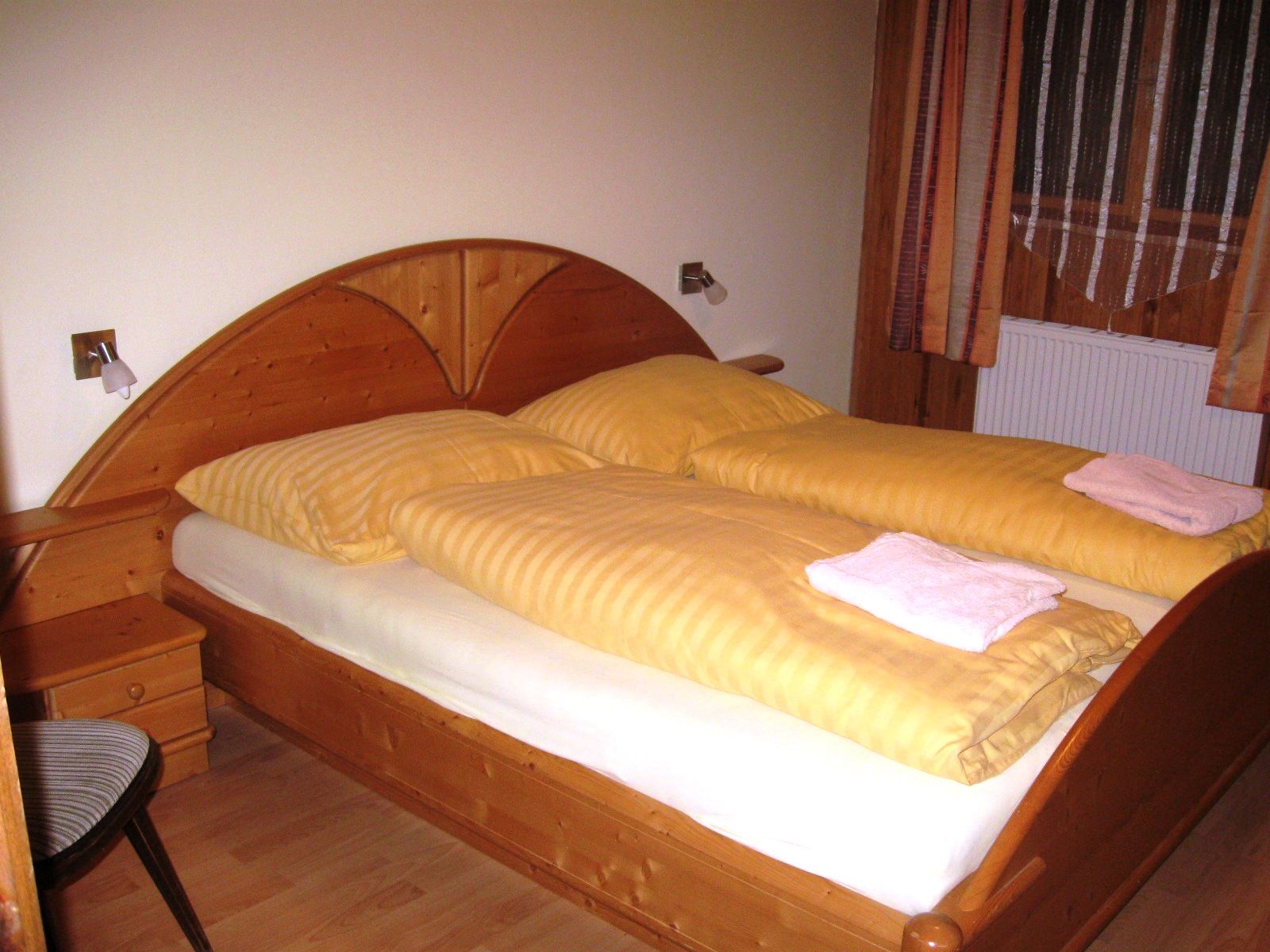 Wooden bed with yellow bed linen in one room.