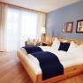 Cozy hotel room with double bed, blue accents and wooden furniture.