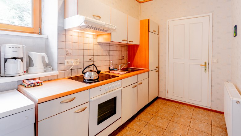Bright kitchen with stove, sink and coffee machine.