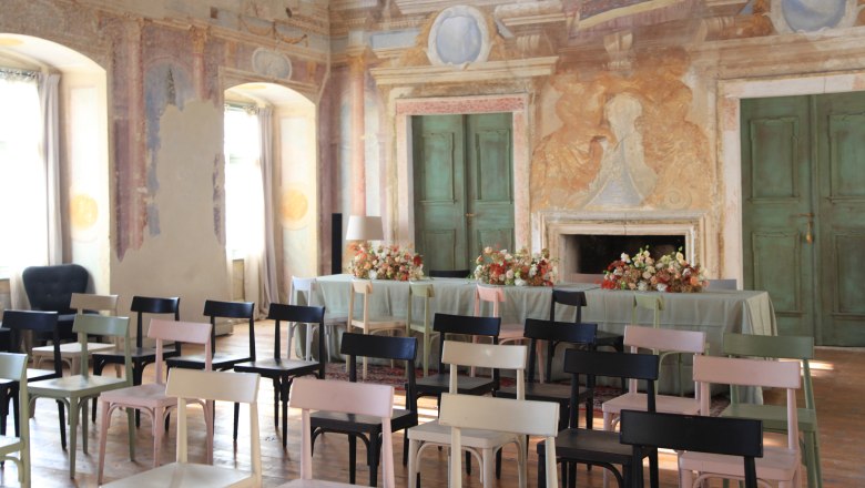 A festively decorated hall with painted walls, chairs and a table with flowers.
