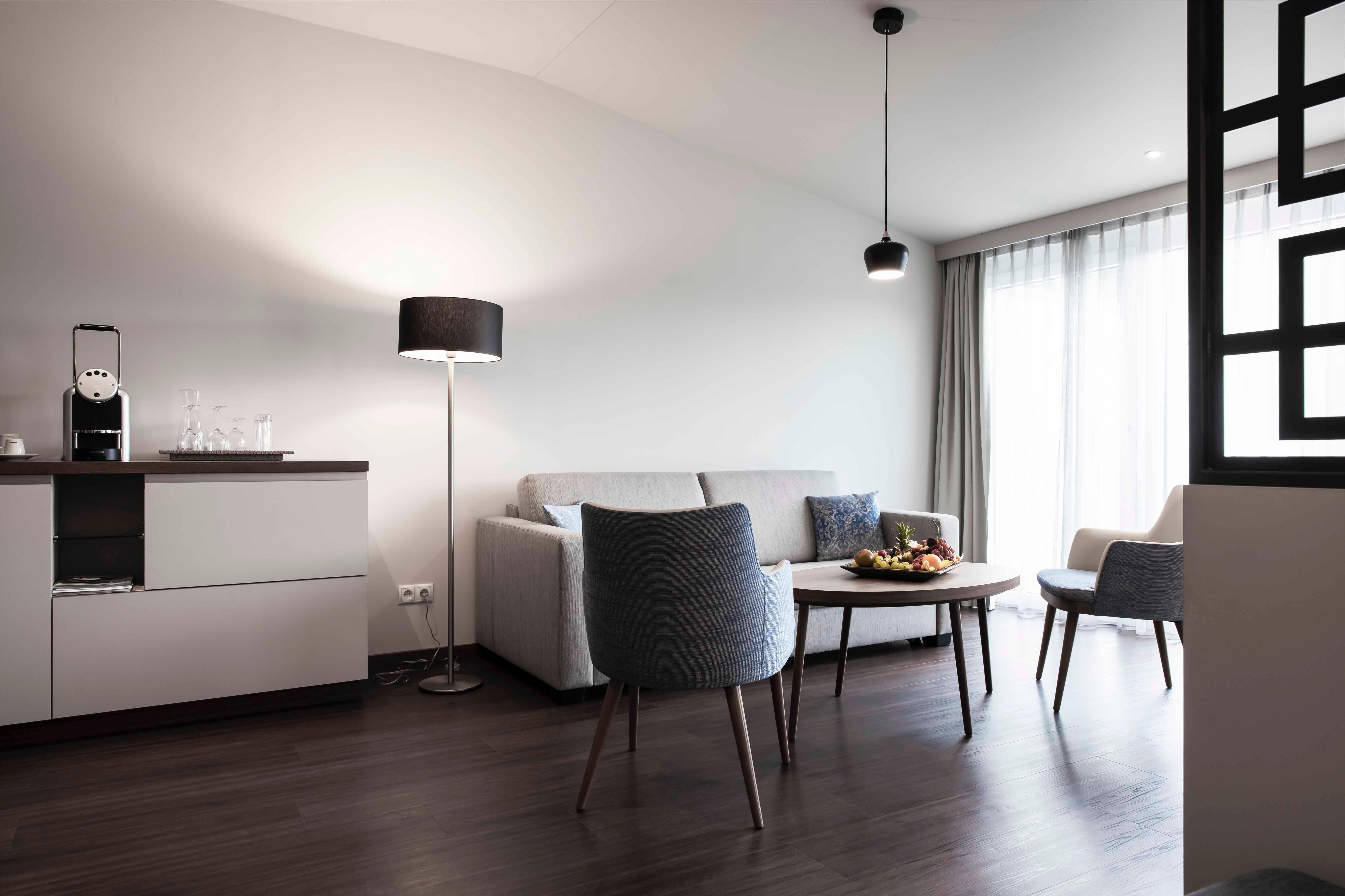 Modern seating area with sofa, armchair, table and floor lamp in a bright room.