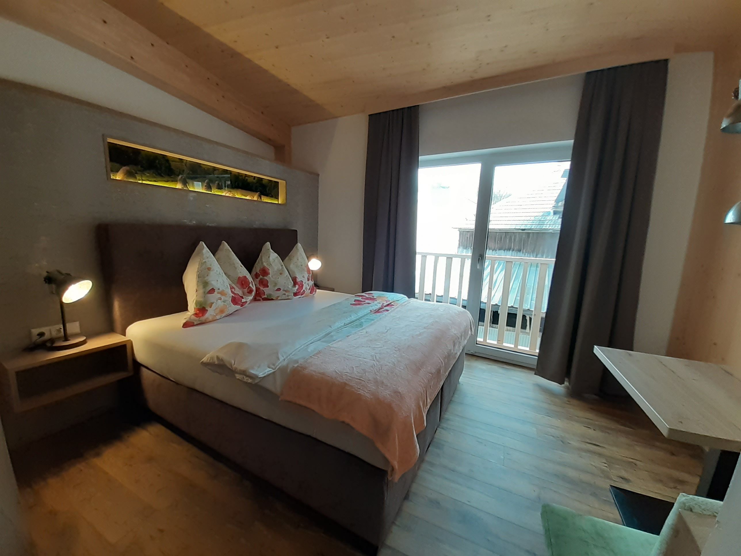 Cozy bedroom with double bed, wooden floor and balcony.
