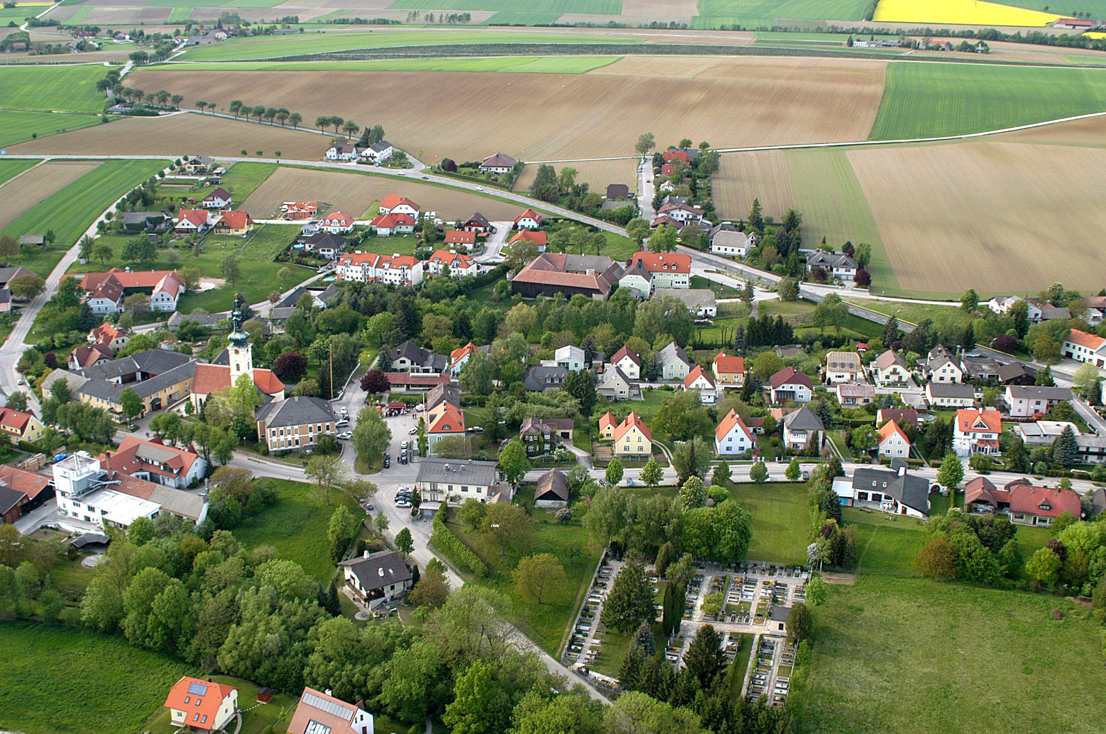 Aerial view of a village with church, houses and fields.