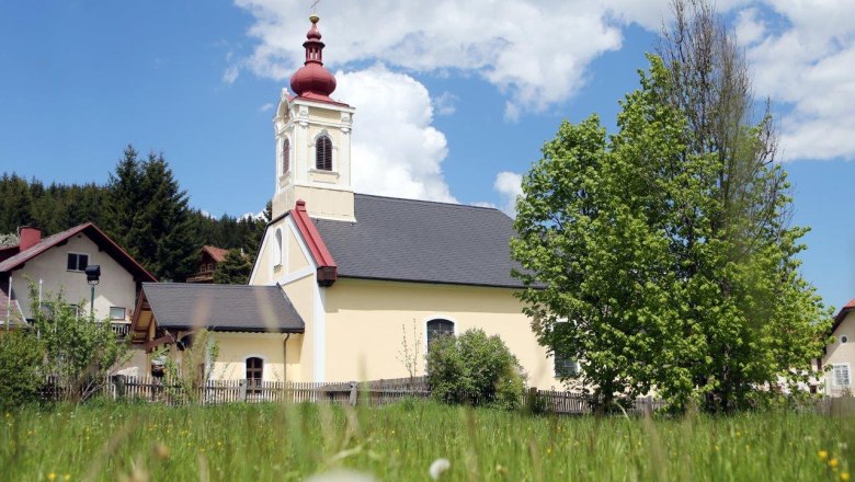 Church in Mitterbach with red tower and green tree in the foreground.