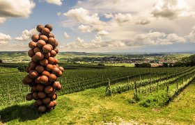 Sculpture of spheres in the shape of a bunch of grapes on a vineyard with a view of a landscape.
