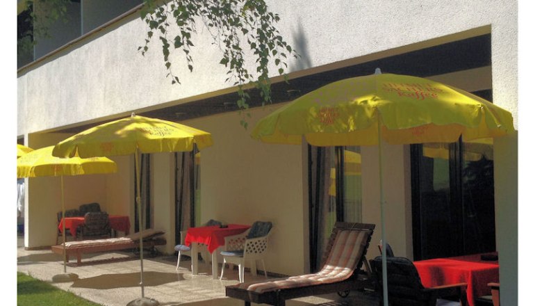 Terrace with yellow parasols and sun loungers in front of a building.
