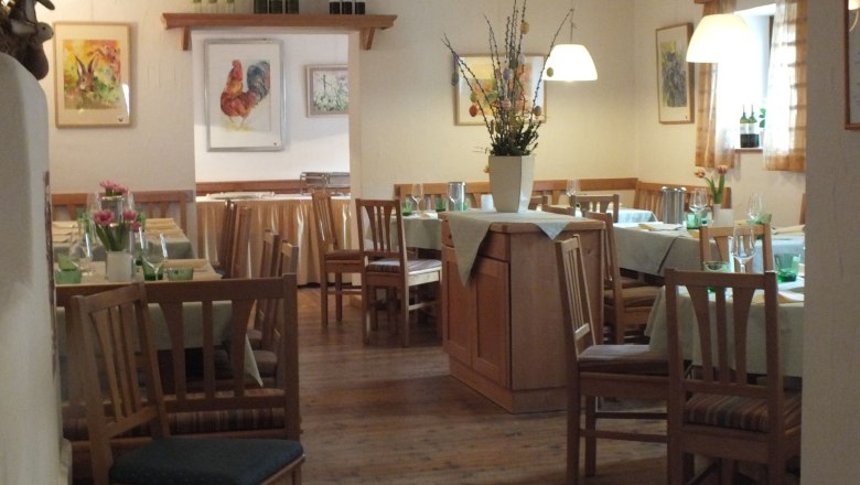 Cozy restaurant with wooden furniture, laid tables and flower vases. Pictures of animals on the walls.