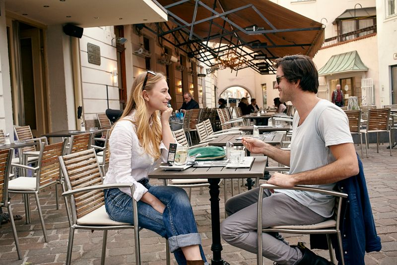 Two people are sitting at a table in a street café and talking.