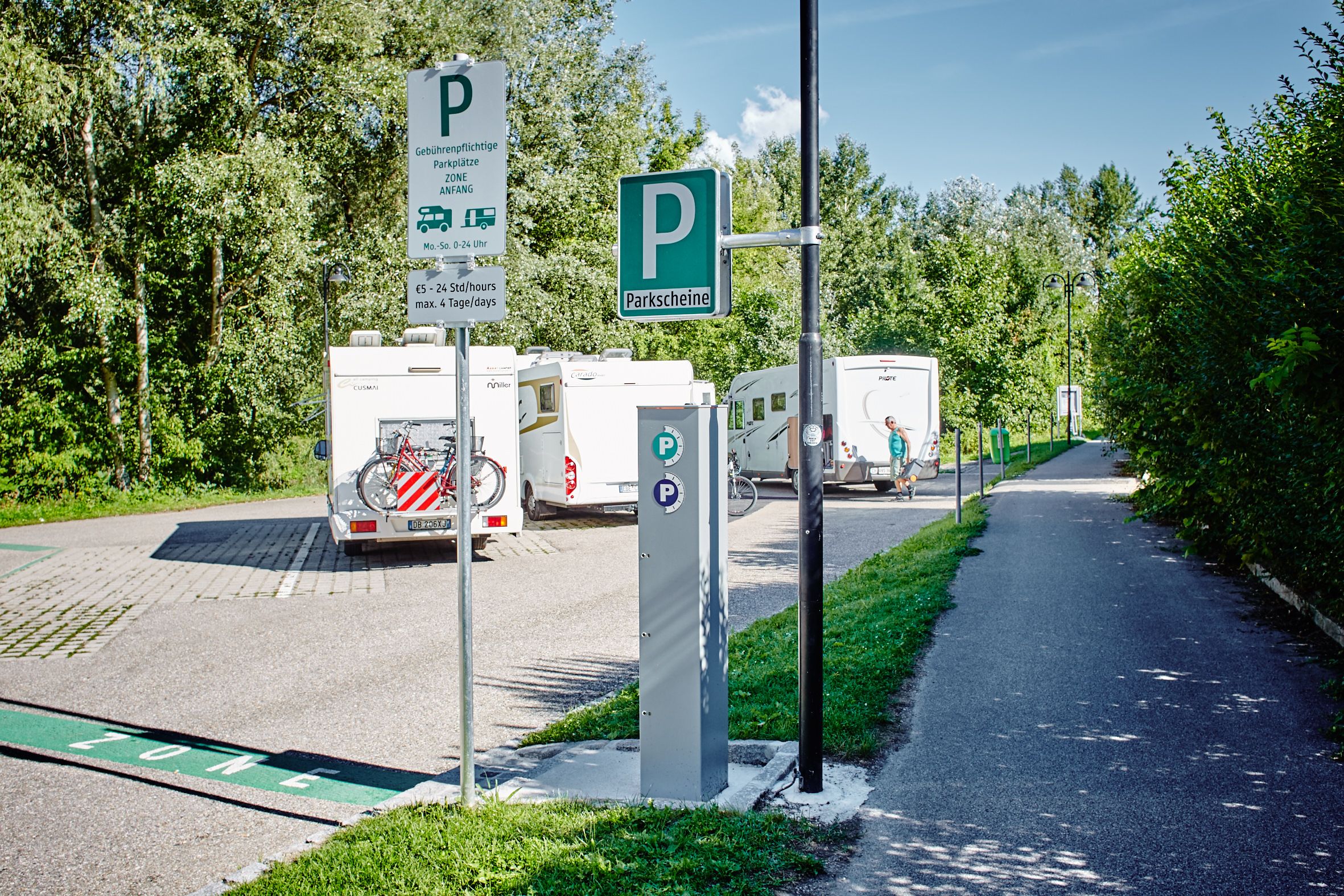 Motorhome parking area with several parked motorhomes and parking ticket machine.