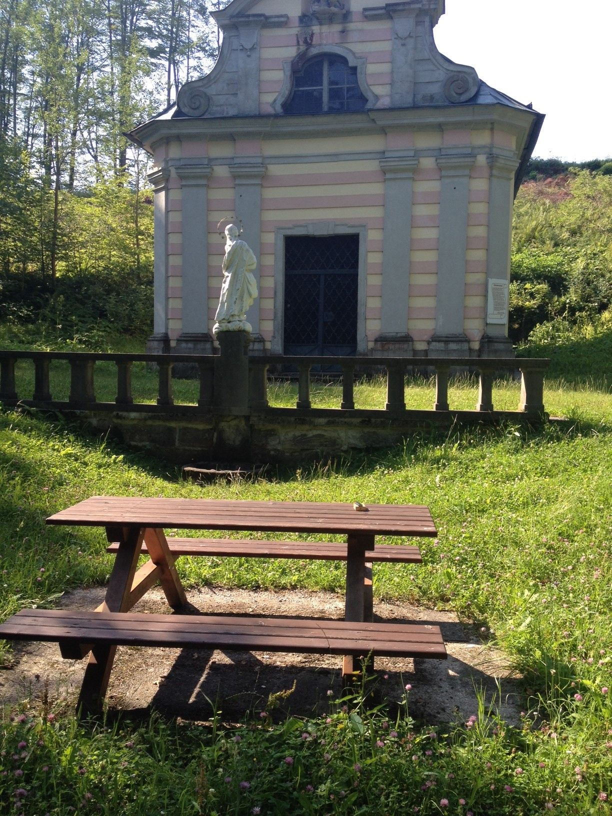 Picnic table in front of a small chapel in the countryside.