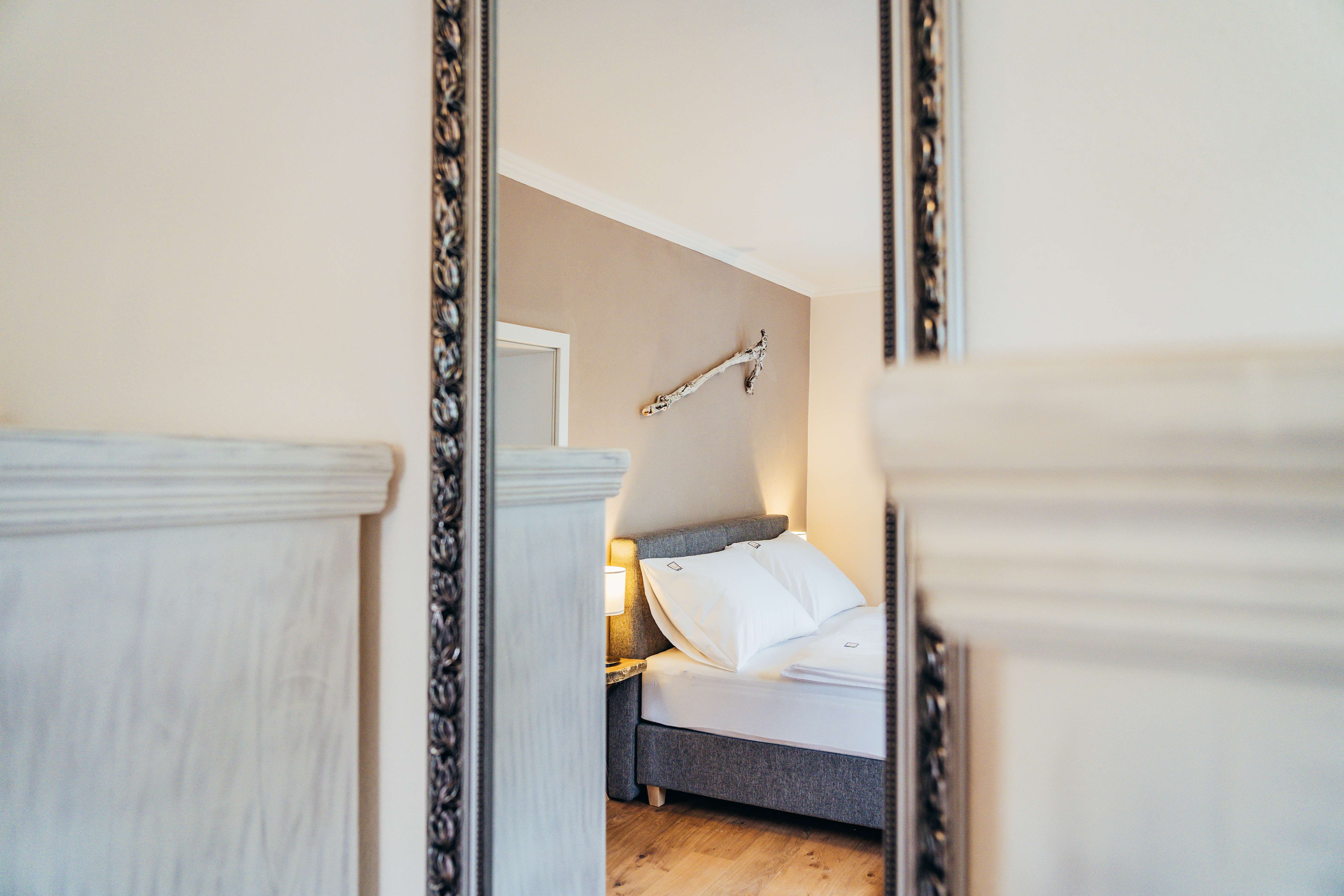 Mirror image of a cozy bedroom with bed and wall decoration.