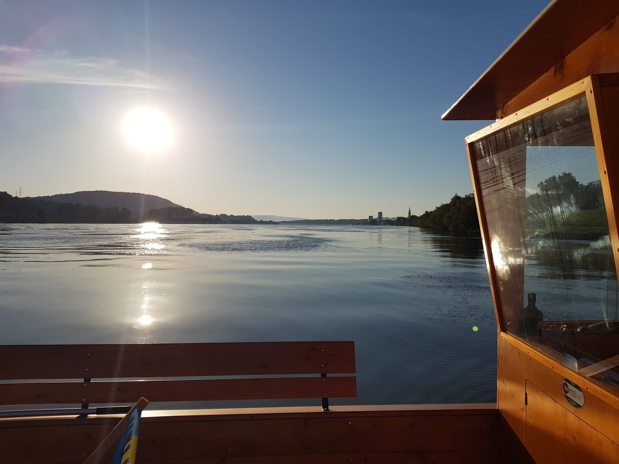 Sunset over a calm river with a wooden boat in the foreground.