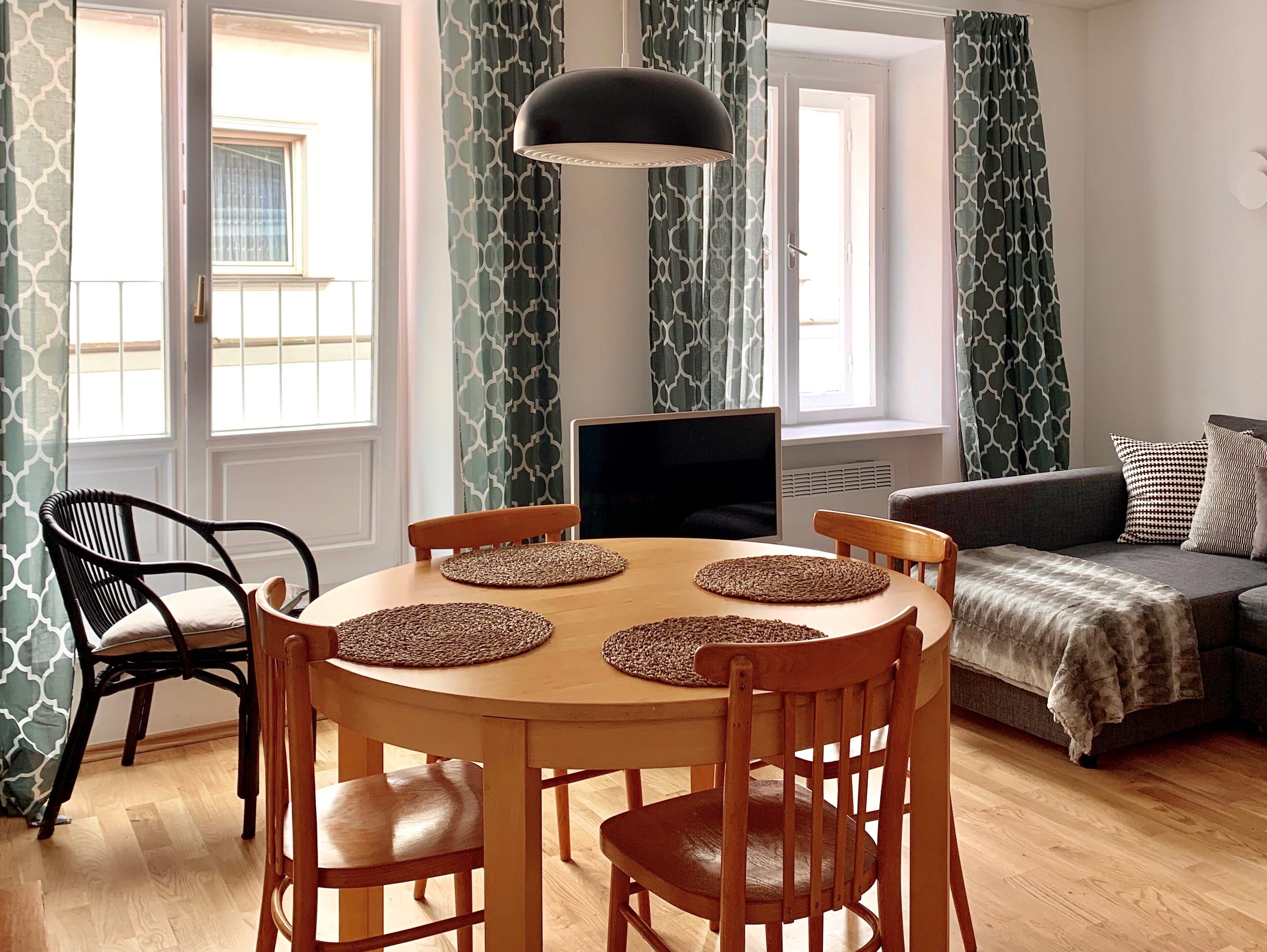 Living room with dining table, chairs, sofa and curtains.