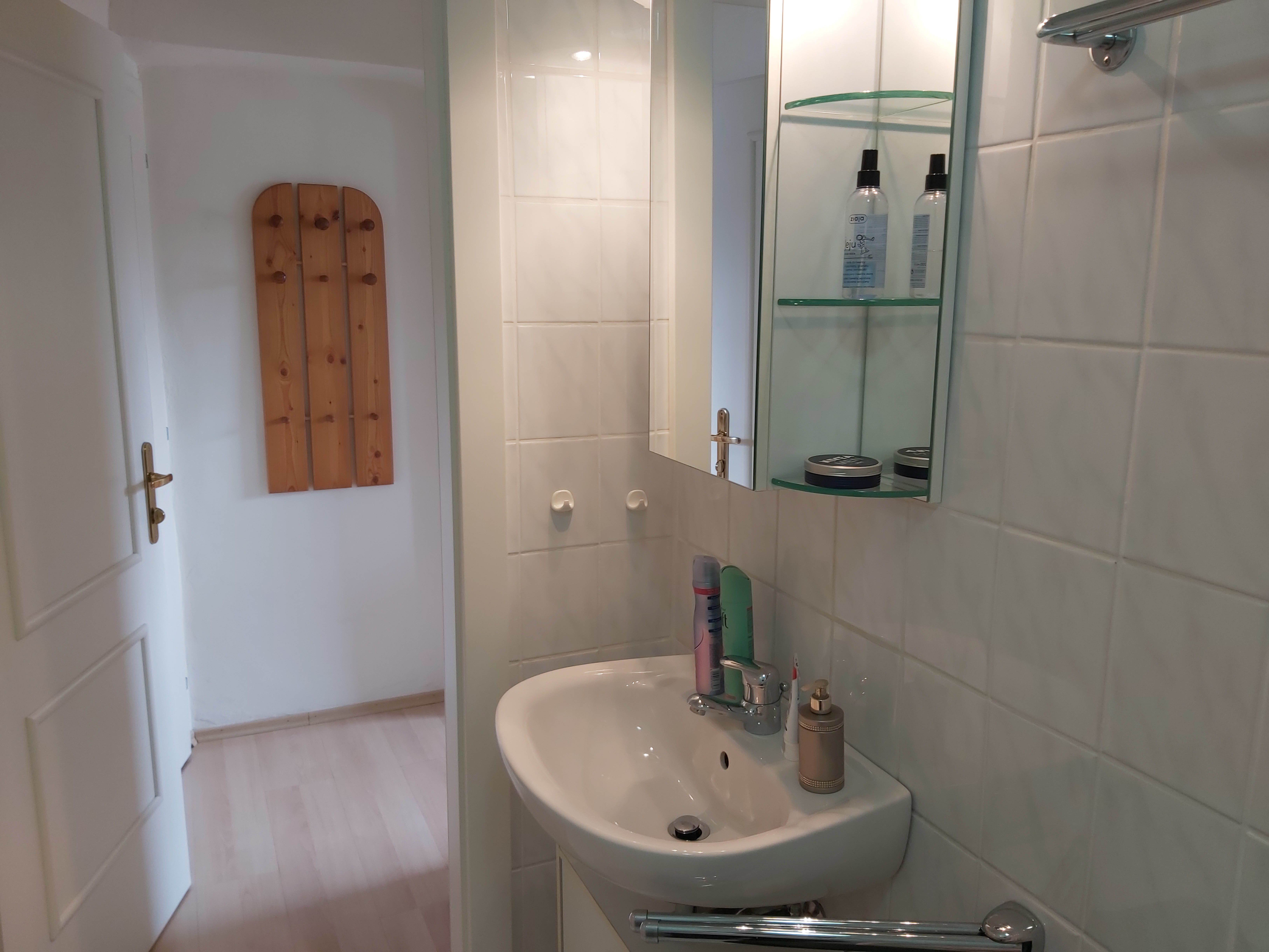 Small bathroom with washbasin, mirror and care products.
