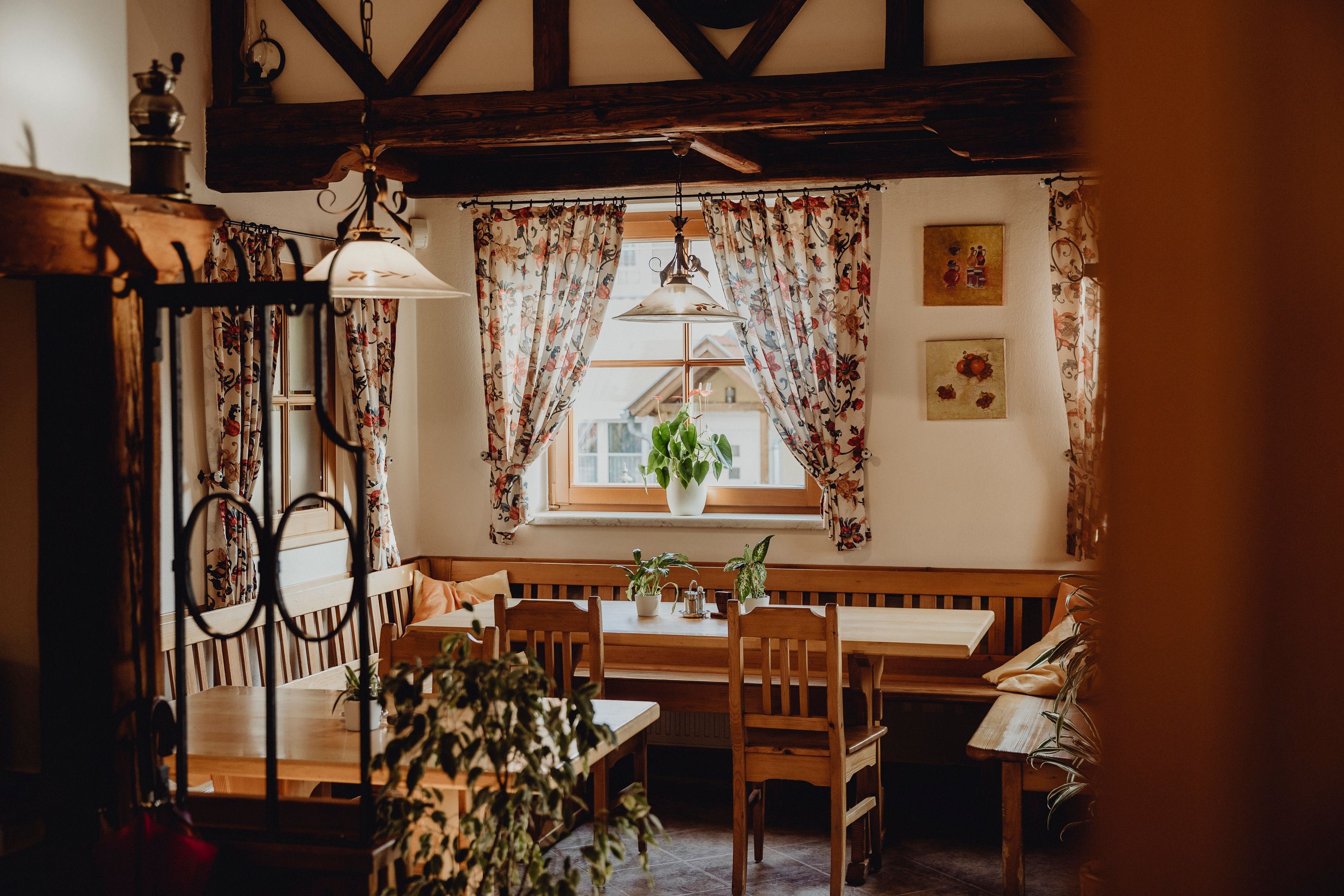 Cozy room with wooden furniture, plants and flowered curtains.
