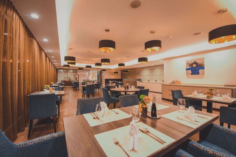 Elegant restaurant with laid tables, blue chairs and modern lighting.