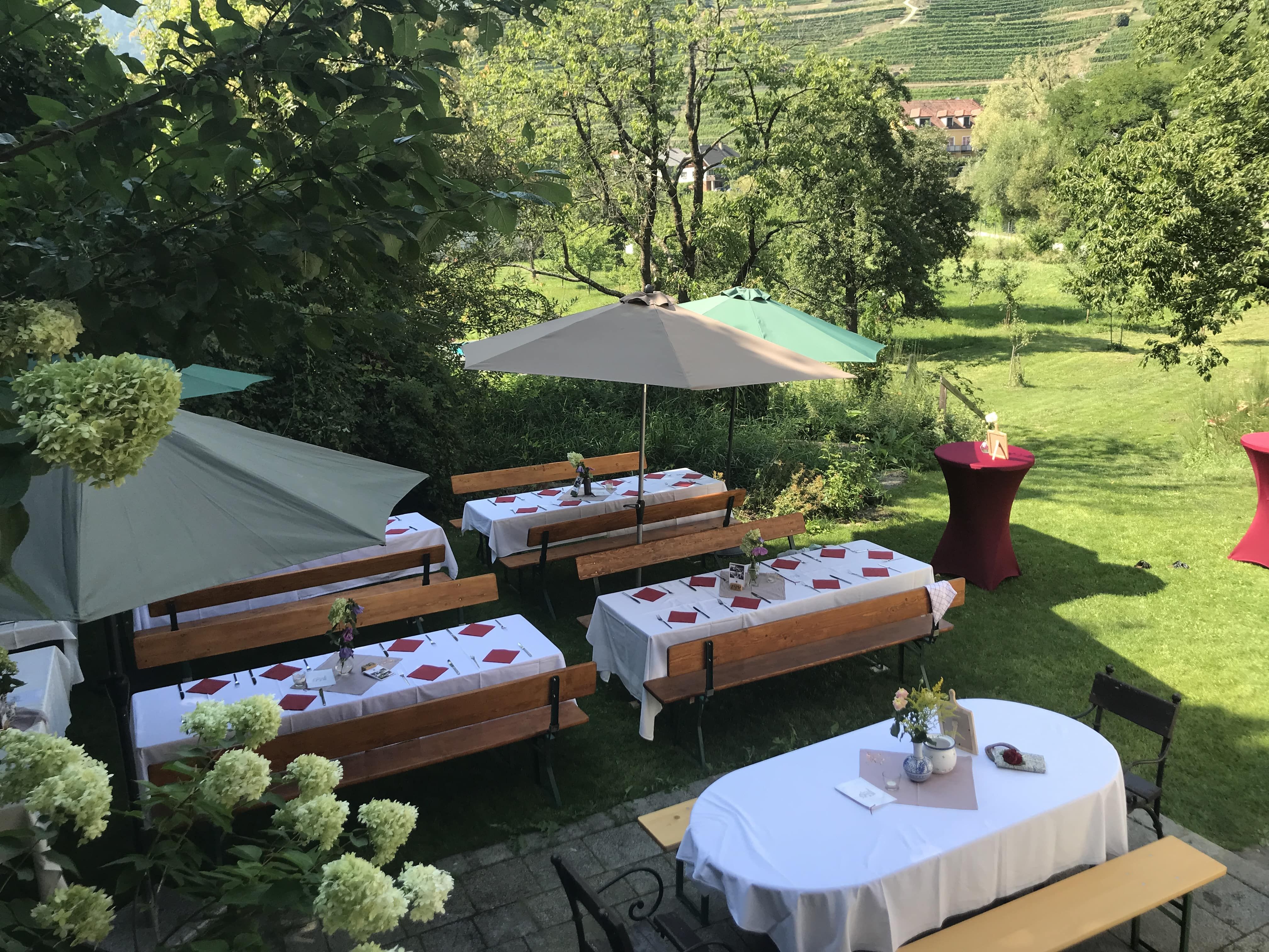 Festively laid outdoor tables with parasols and flower arrangements.