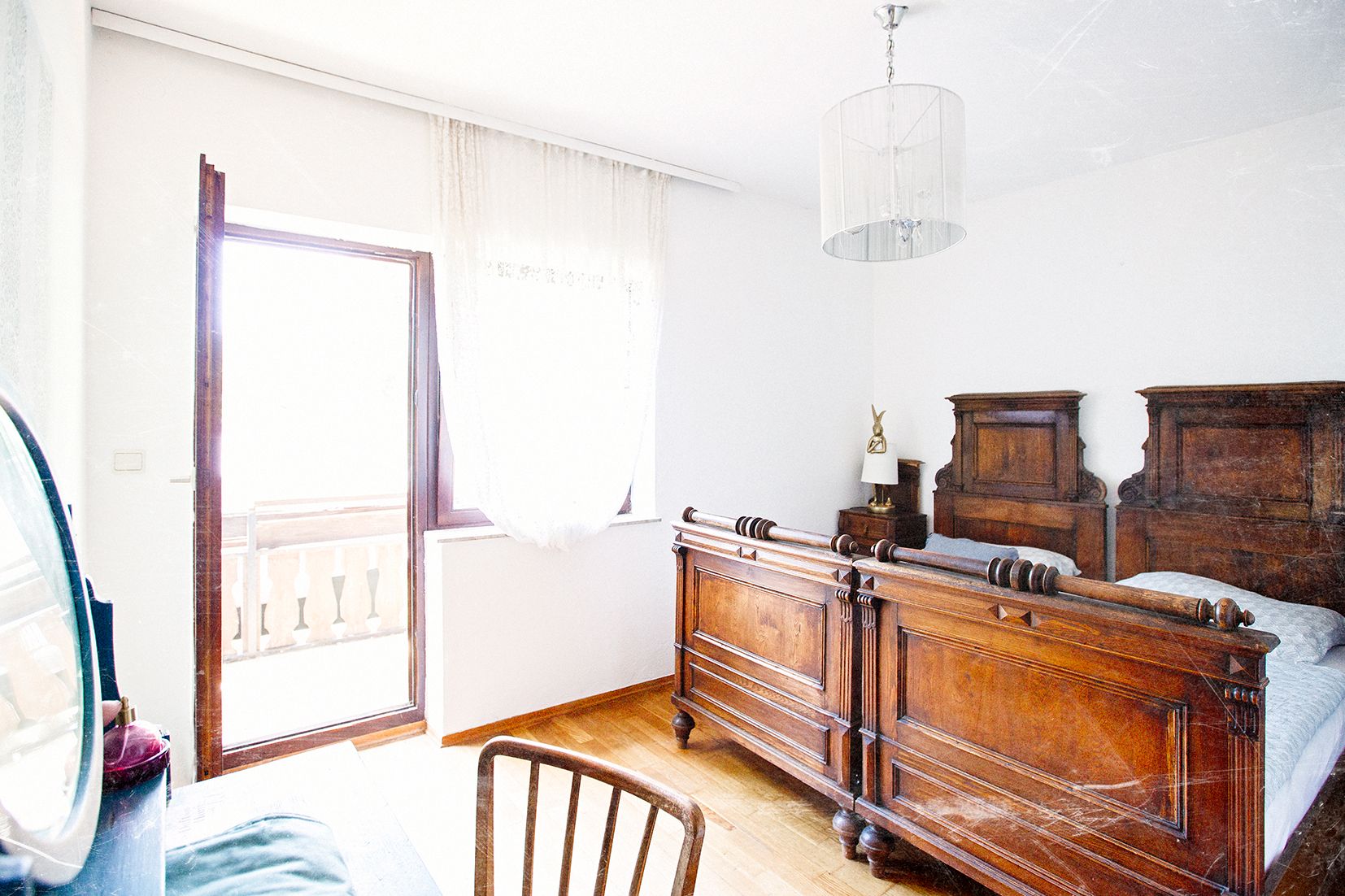 A bright bedroom with antique wooden furniture and access to a balcony.