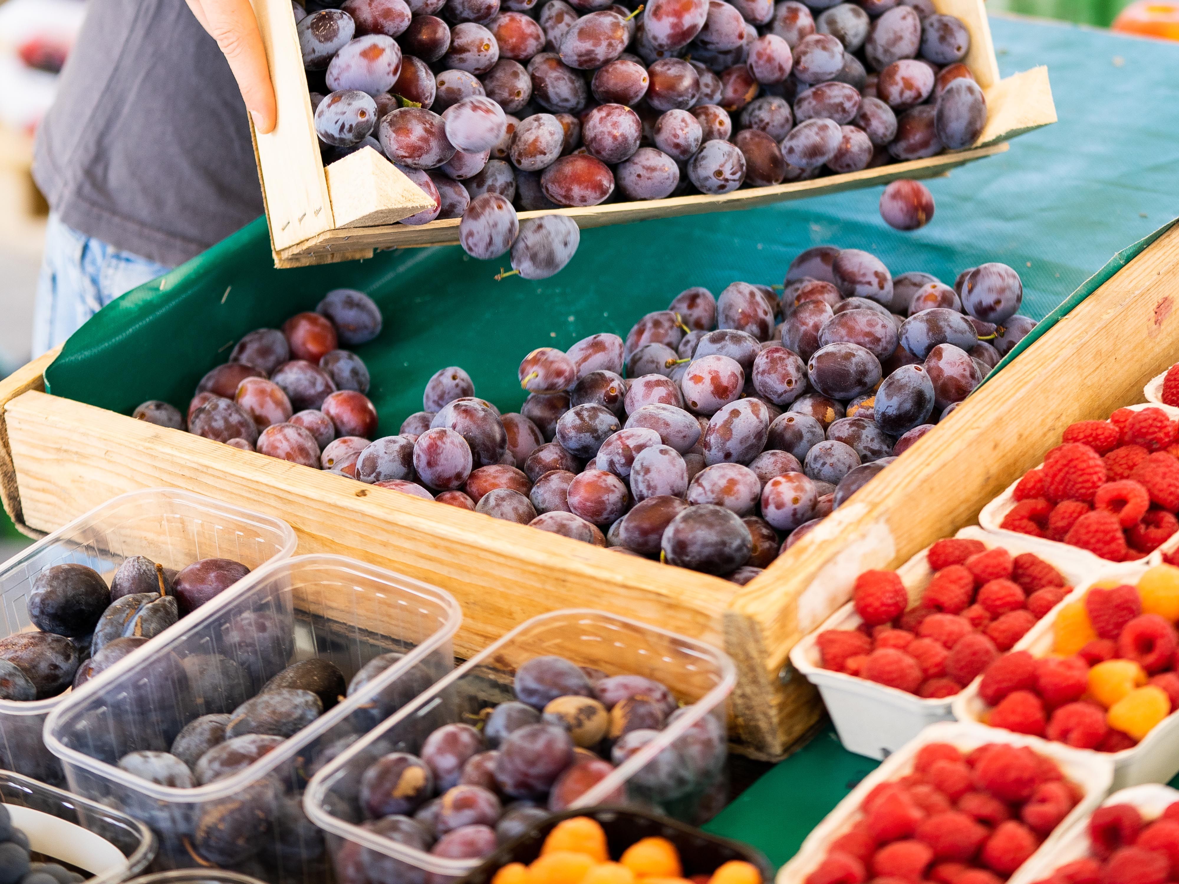 Plums and raspberries on a market stall.