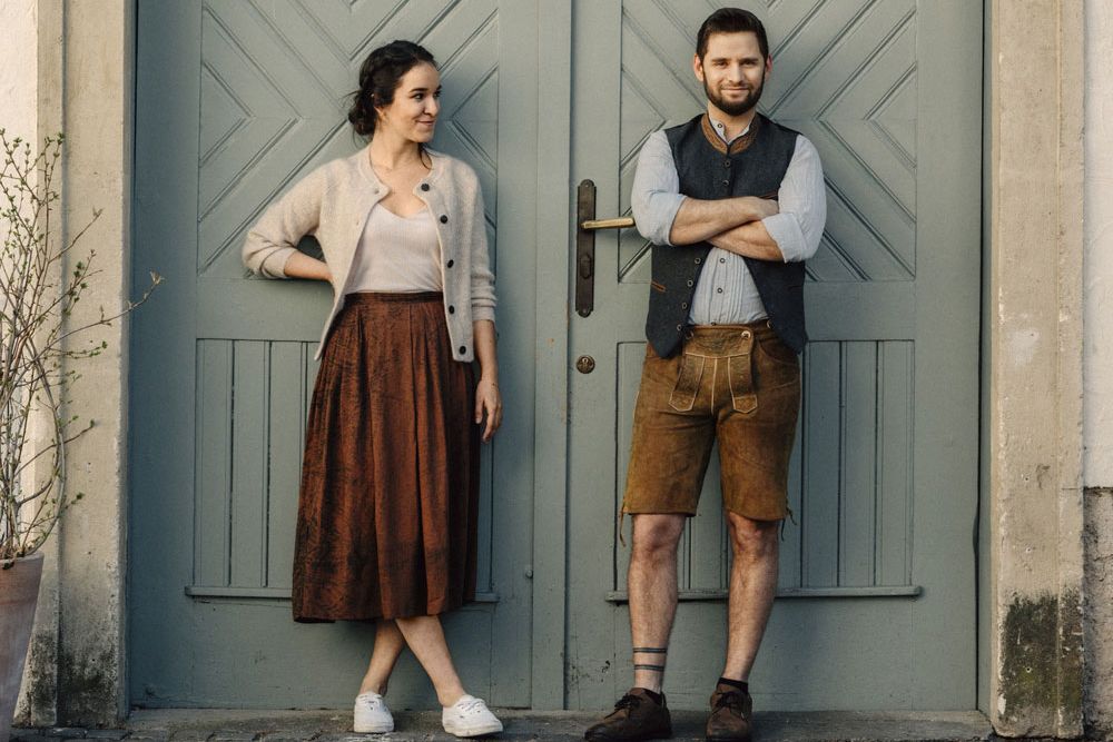 Two people in traditional dress in front of a blue wooden door.