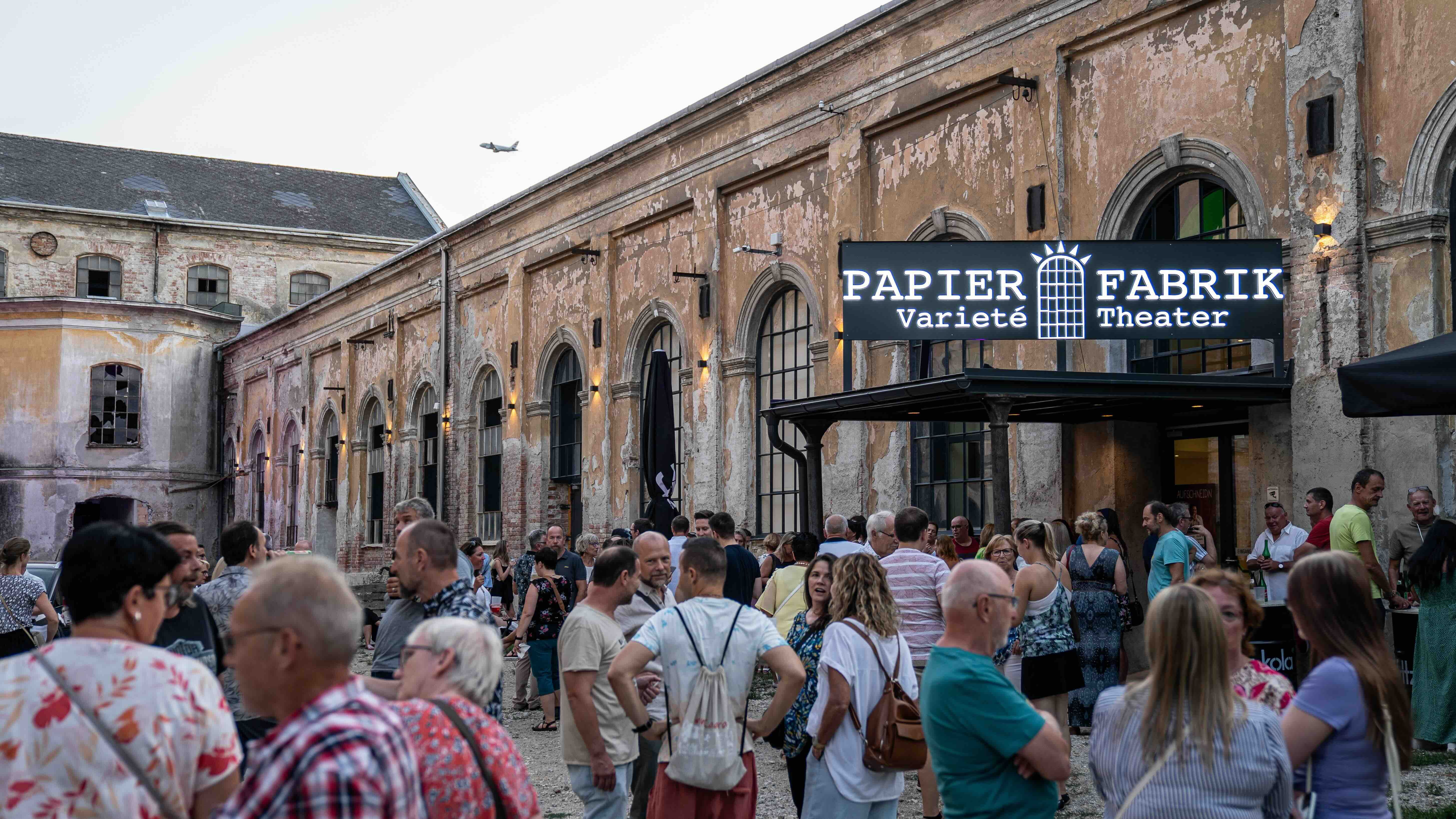 Crowd in front of an old paper factory with a sign 'Papier Fabrik Varieté Theater'.