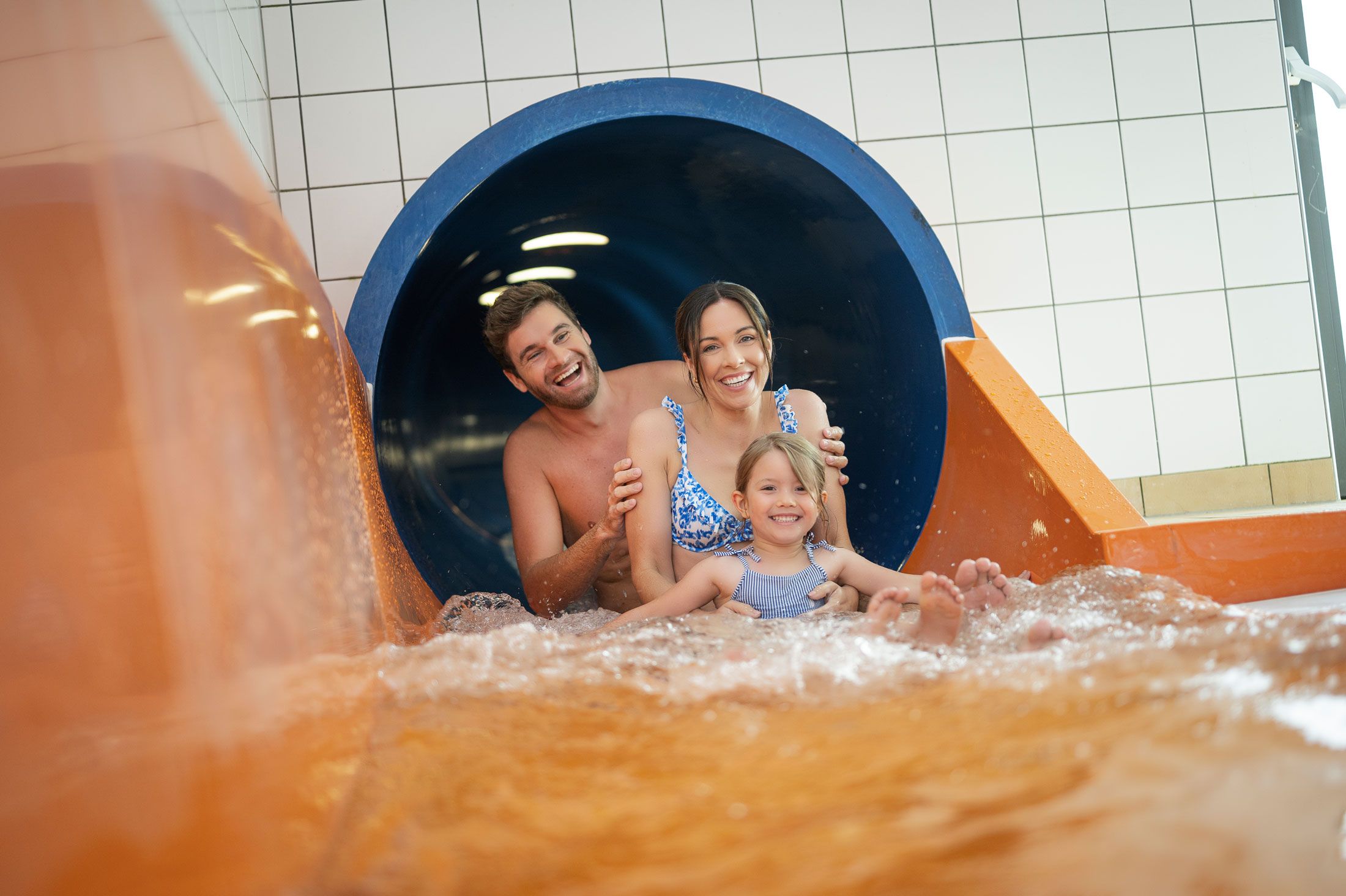 A laughing family slides down a water slide.