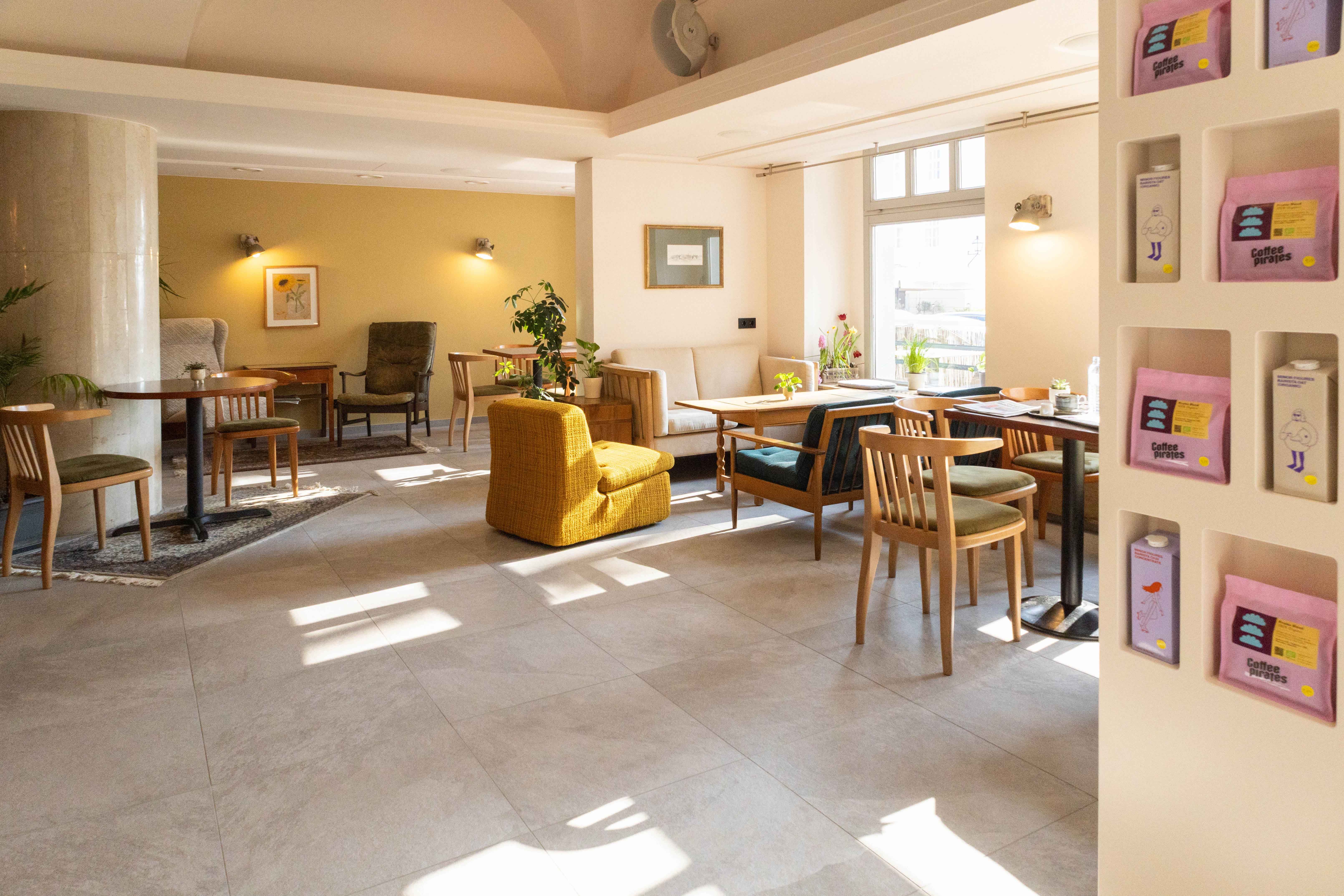 Interior view of a cozy café with wooden furniture and plants.