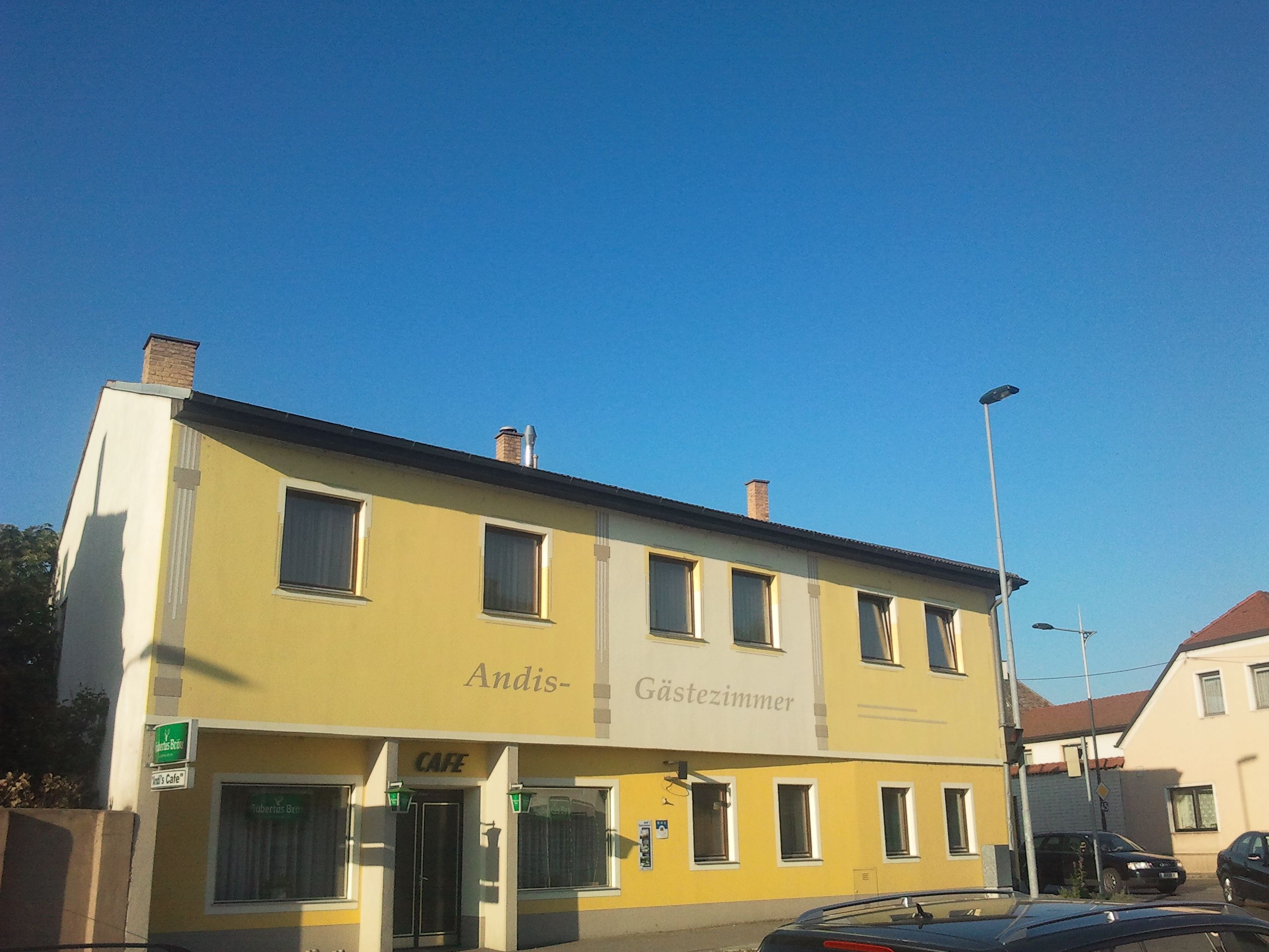Yellow building with the inscription 'Andis Gästezimmer' and 'Cafe'.