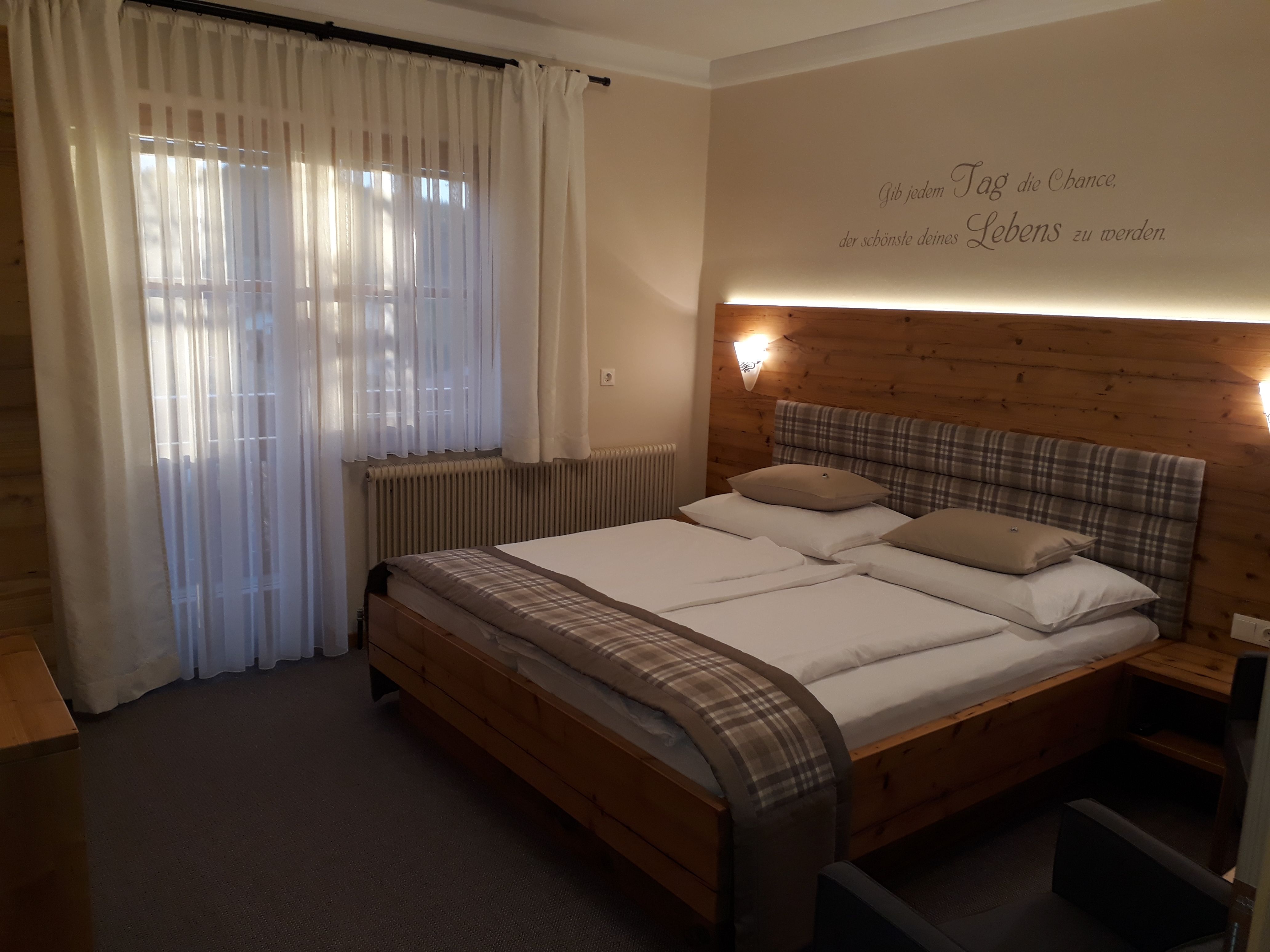Cozy bedroom with double bed, wooden wall and curtains.