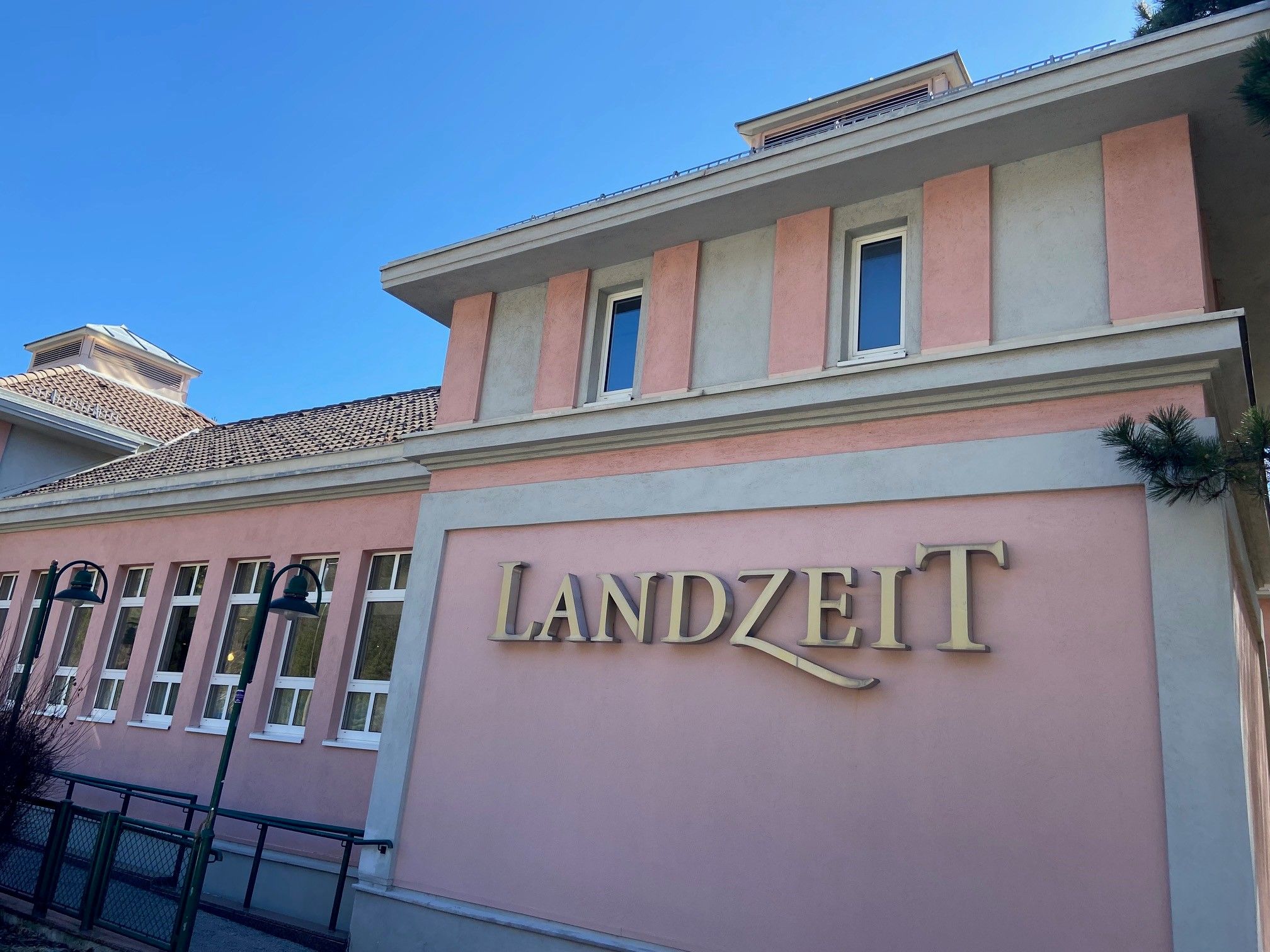 Building with a pink façade and the lettering 'Landzeit'.