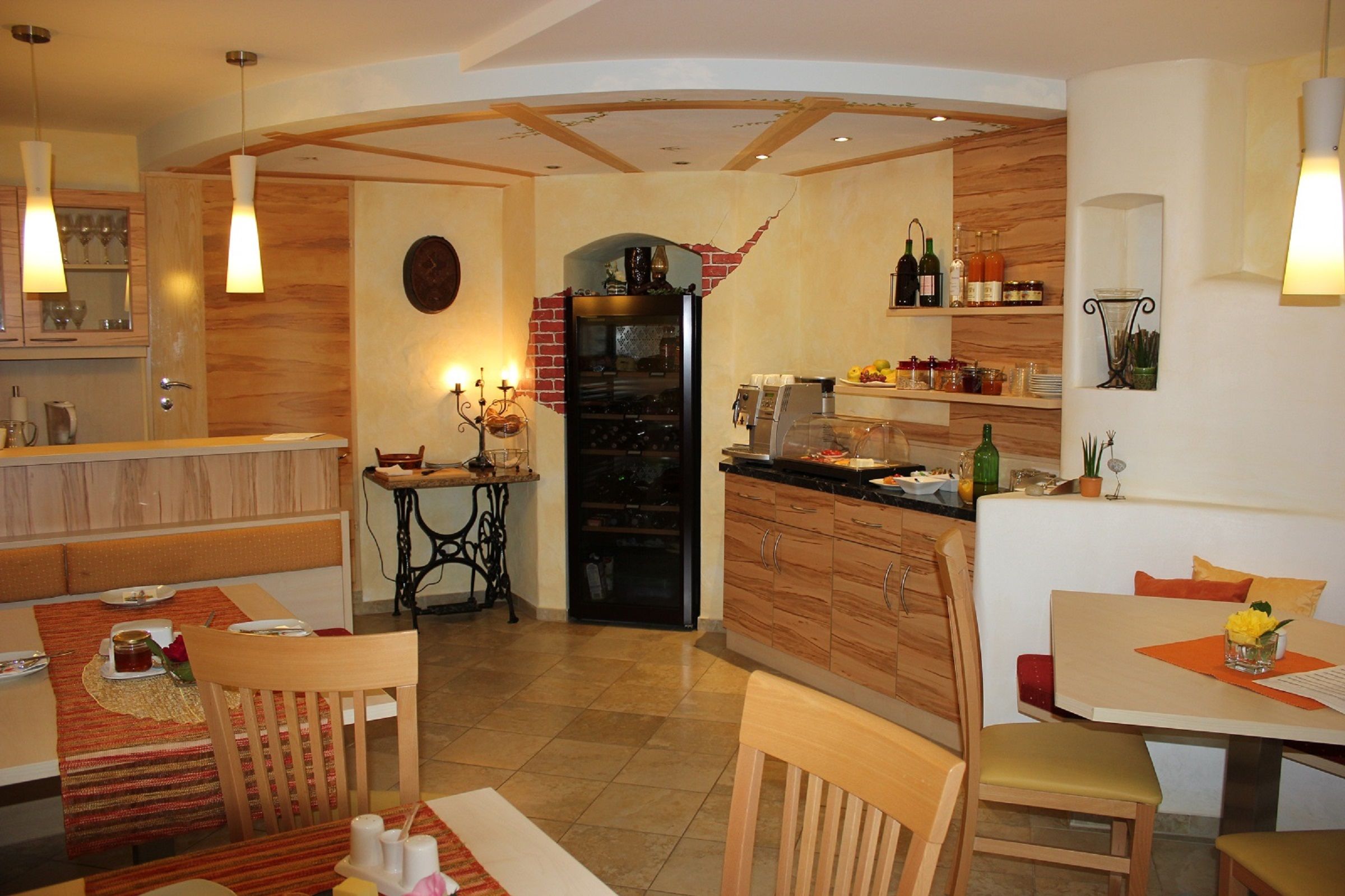 Cozy breakfast room with wooden furniture, laid tables and a buffet with drinks and food.