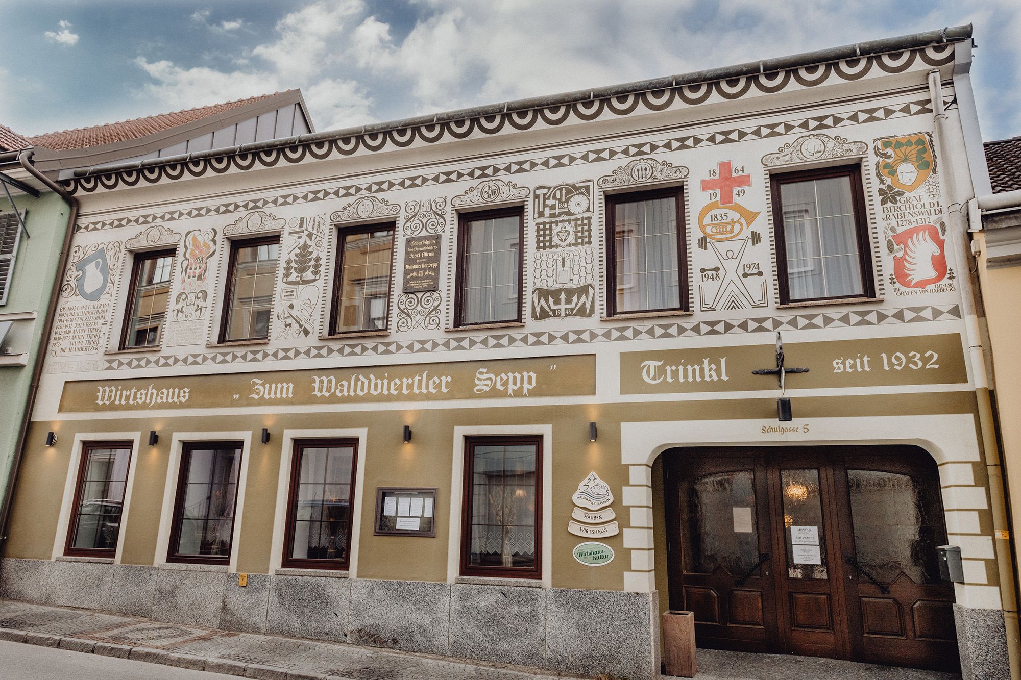 Façade of a traditional inn with decorative paintings and the lettering "Zum Waldviertler Sepp" in Schrems.